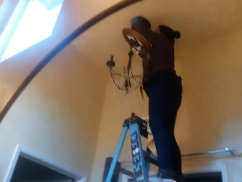 Electrician installing a chandelier in a Elmendorf residence